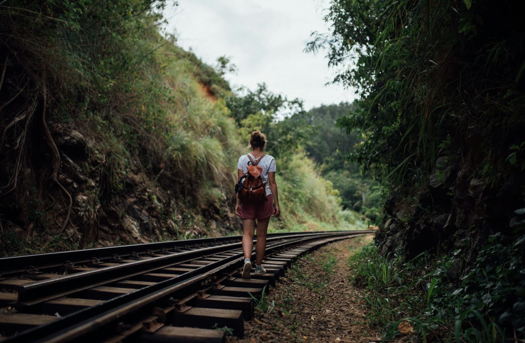 A woman hiking along railroad tracks