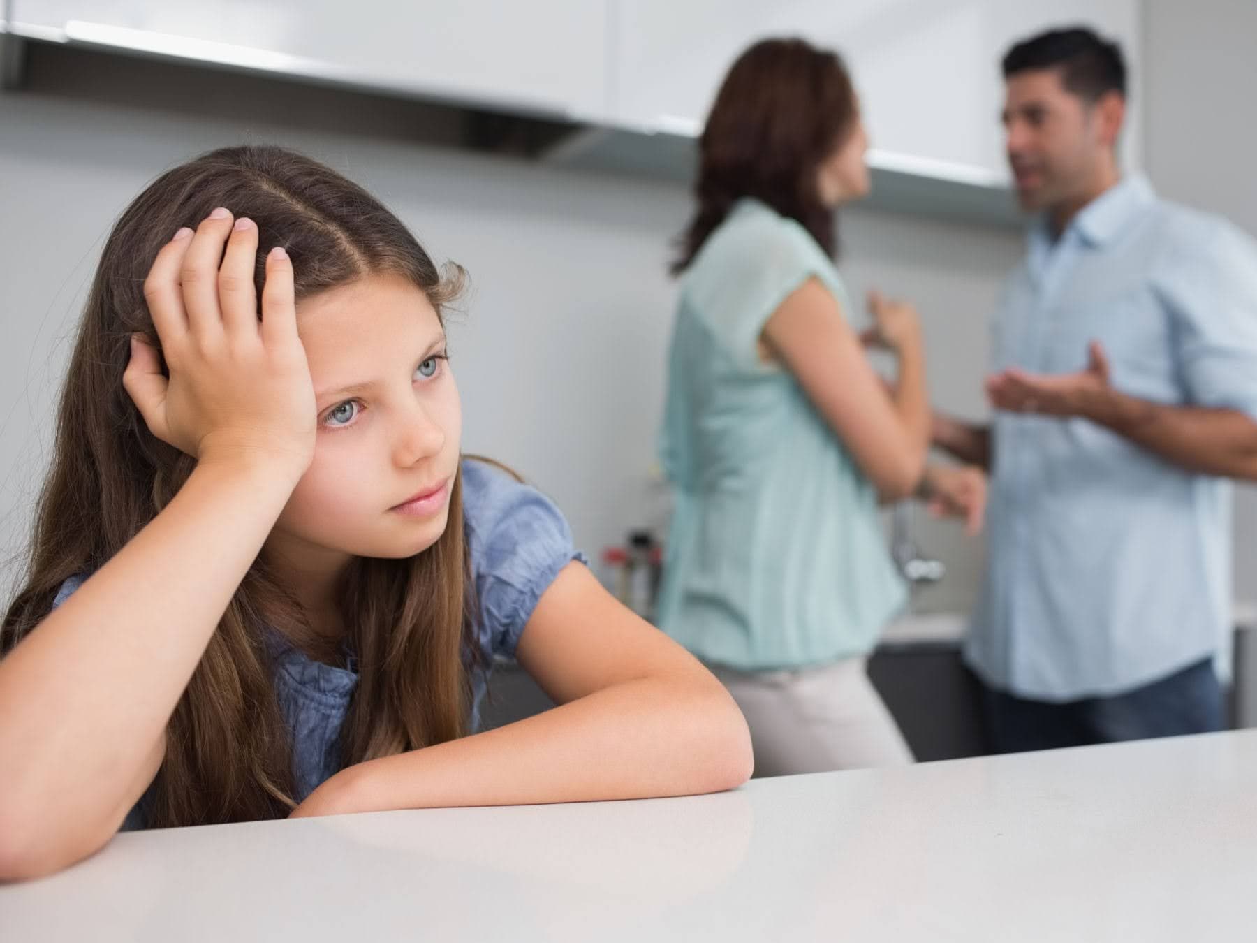 Parents arguing in a kitchen with their child in the foreground